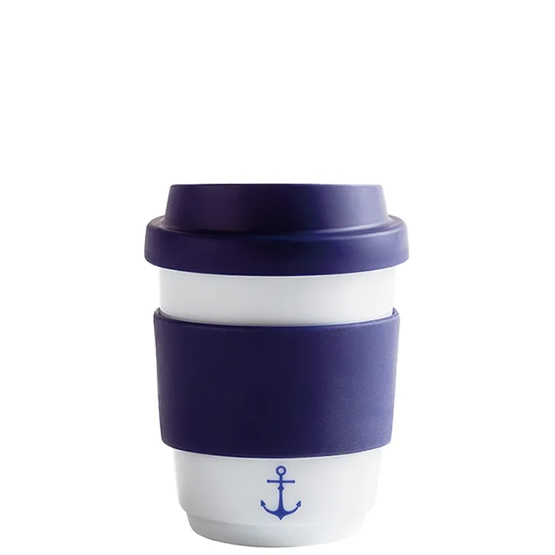 Ein becherförmiger To-Go-Becher aus Keramik, der mit einem tiefvioletten Silikonring und einem Deckel ausgestattet ist. Der Becher ist weiß mit einer blauen Ankerabbildung an der Vorderseite. Der Silikonring sorgt für einen sicheren Halt und schützt vor Hitze. Insgesamt vermittelt das Design ein maritimes Flair und ist ideal für den Genuss von heißen Getränken unterwegs.