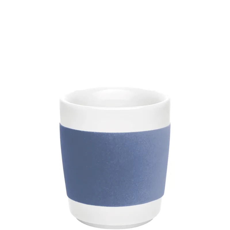 Ein moderner Keramikbecher mit einem weißen oberen Rand und einer matten blauen Umrandung am unteren Teil. Der Becher hat eine schlichte, elegante Form und eine glatte Oberfläche. Er steht auf einer weißen Unterlage und reflektiert sanft das Licht. Der Innenraum des Bechers ist ebenfalls weiß. Ideal für heiße Getränke wie Kaffee oder Tee.