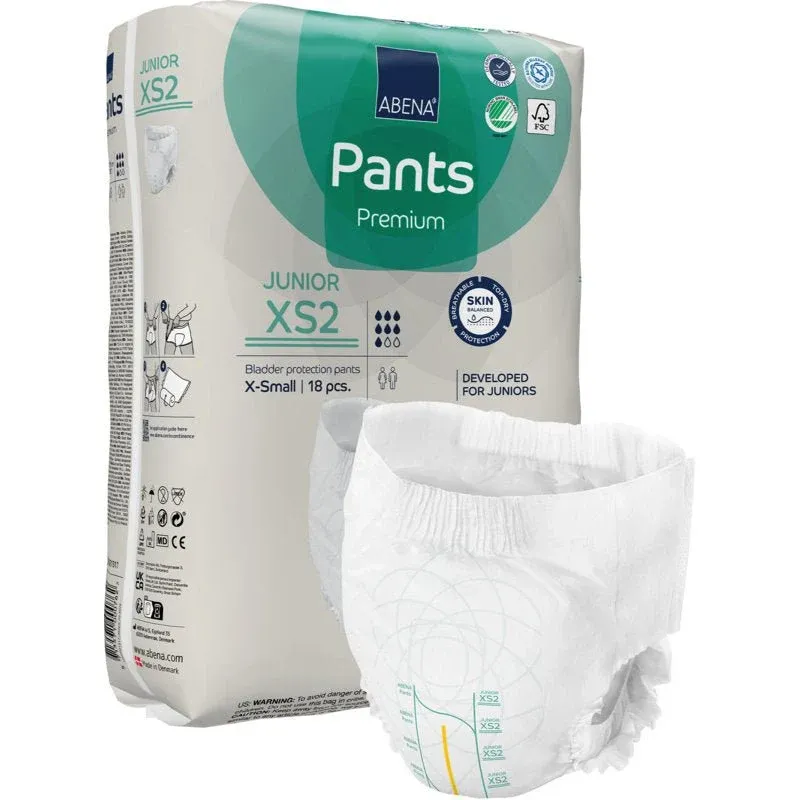 Eine Packung ABENA Pants Junior Premium, Gr. XS2 von Abena Re-Seller GmbH wird mit einer ungefalteten Windel im Vordergrund gezeigt. Die beigefarbene Packung mit grünen und blauen Akzenten enthält 18 Stück X-small.